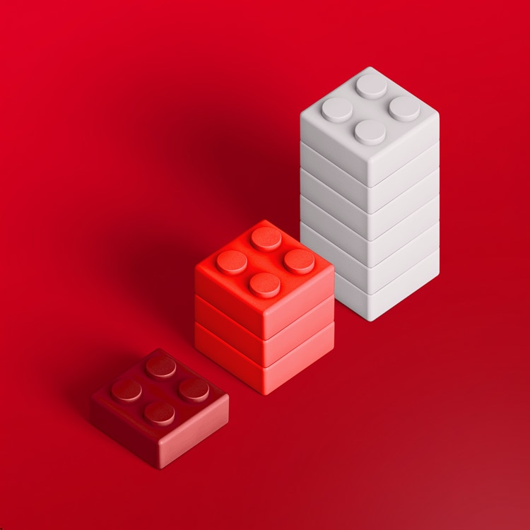 Three toy building block stacks in different heights on a red background, arranged from shortest to tallest.