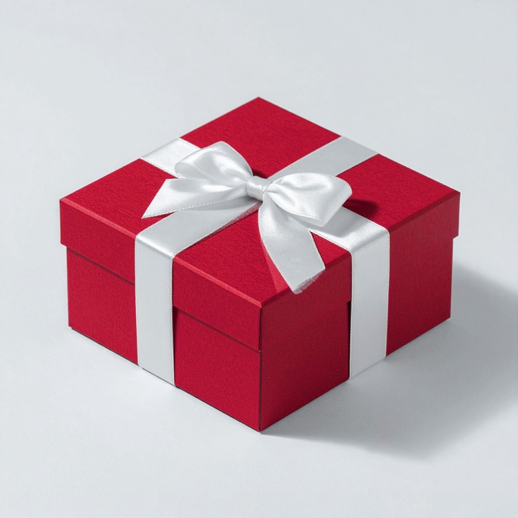 Red gift box with a white satin ribbon tied in a bow, placed on a light gray surface.