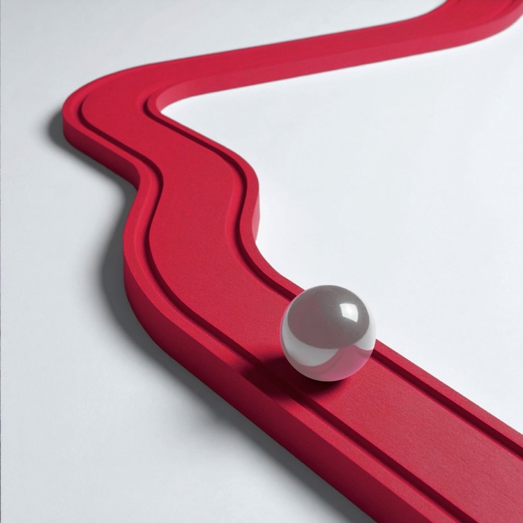 Glossy white sphere resting on a curved red track with two parallel grooves, set against a white background.