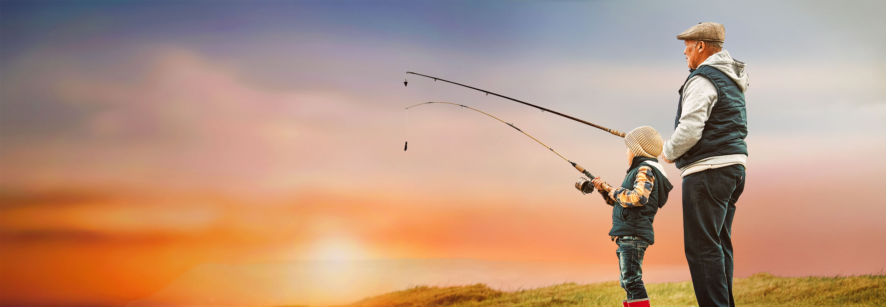 old man and young boy fishing against sunrise