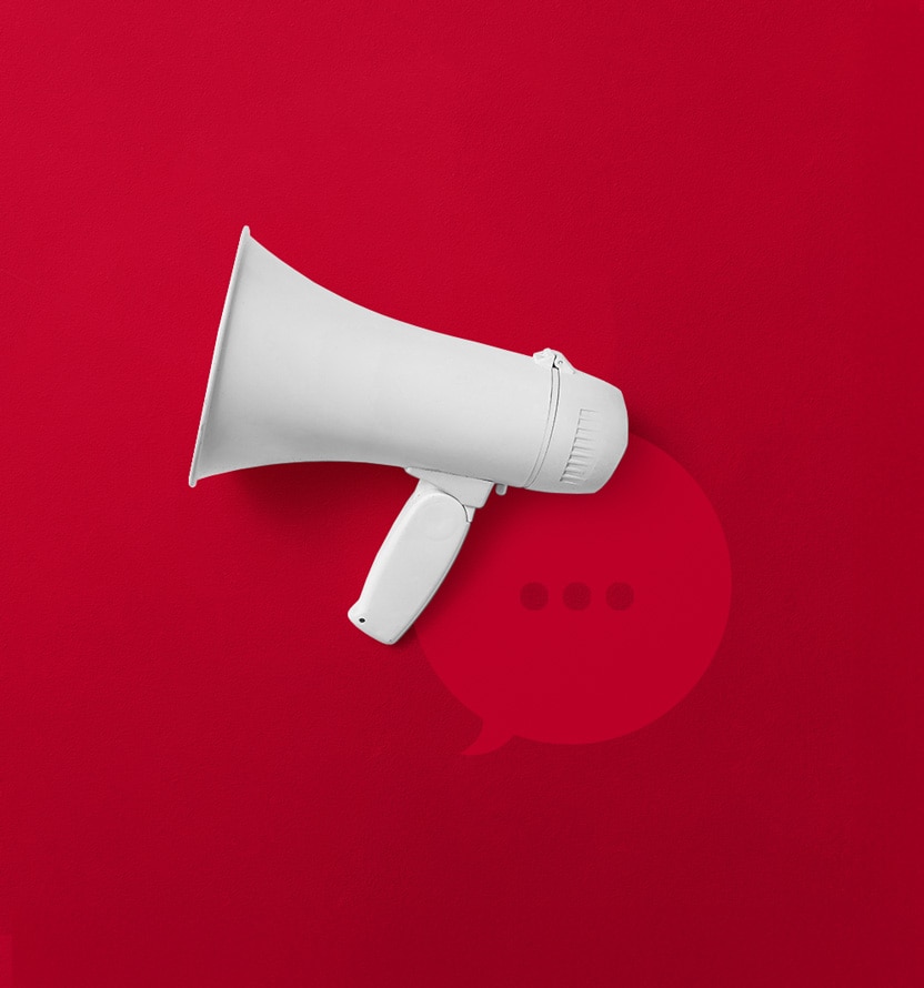 White megaphone positioned on a bright red background, with a subtle speech bubble icon and three dots behind it, symbolizing communication, announcements, or messaging.