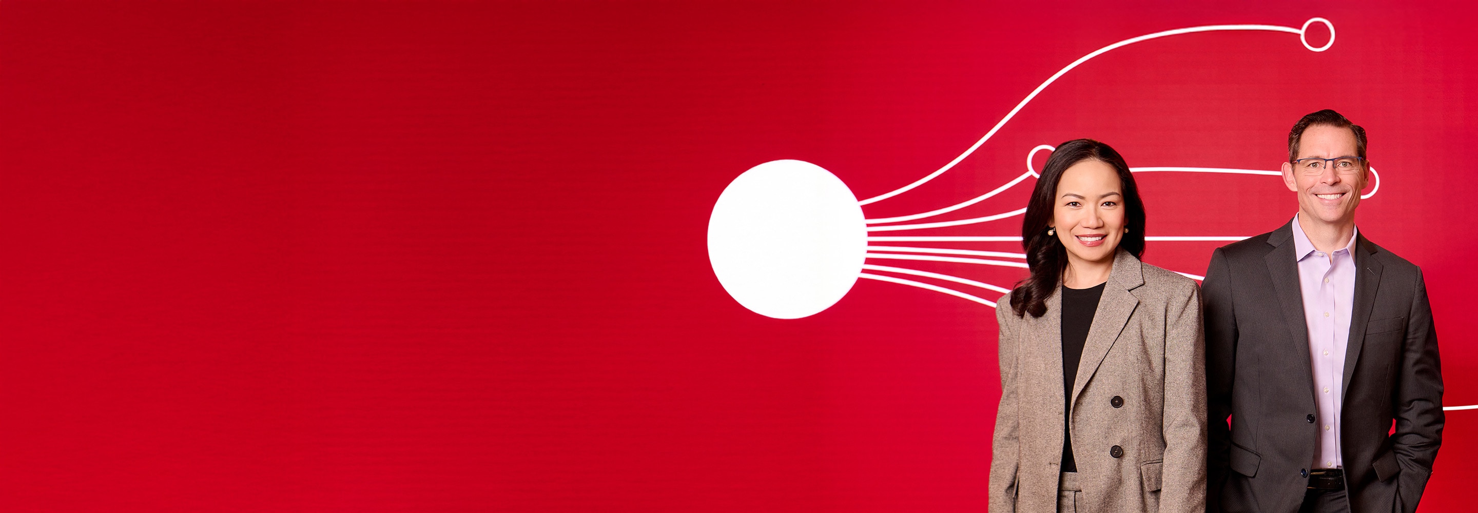Christine Kashkari (left) and Joe Davis stand in front of a red background with abstract white line graphics.