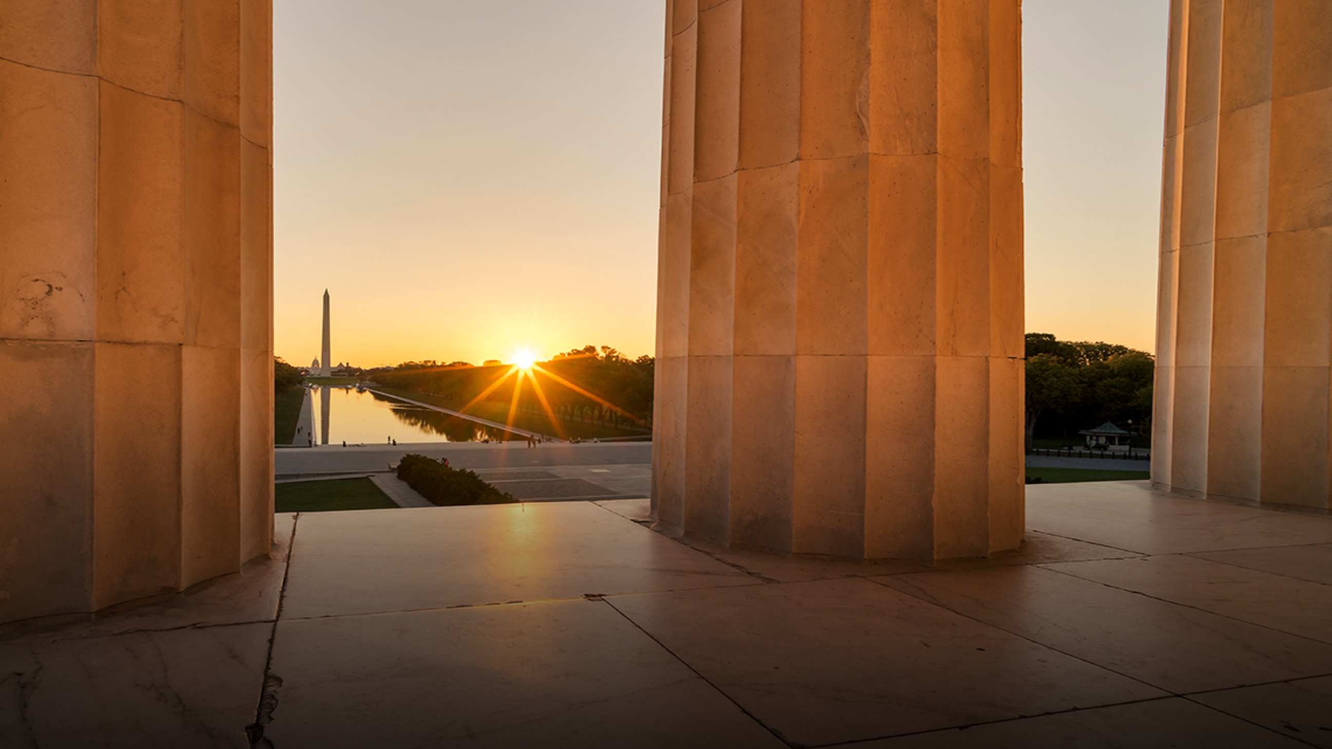 A vista of sun, calm water, and enduring monuments