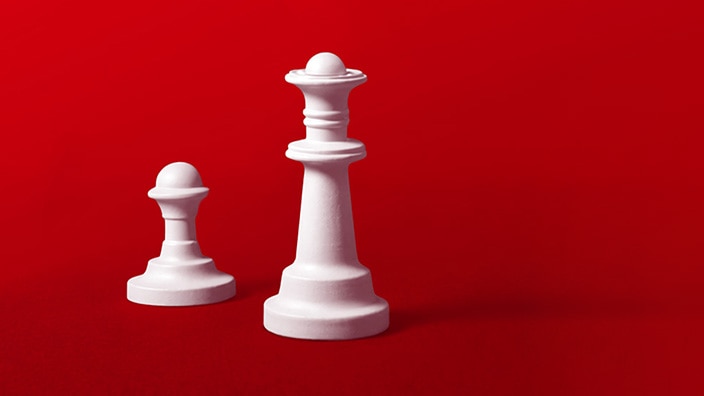 White chess queen and pawn standing side by side on a red background.