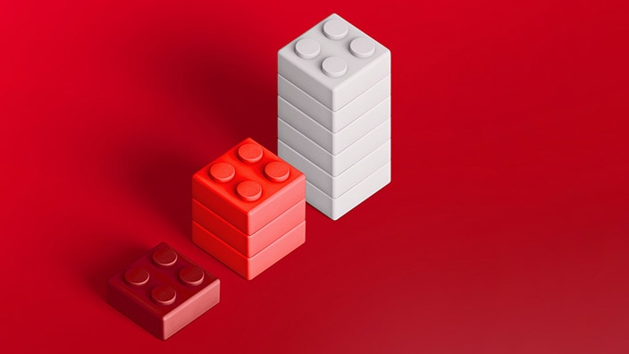 Three toy building block stacks in different heights on a red background, arranged from shortest to tallest.