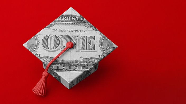 Origami graduation cap folded from a U.S. dollar bill with a red tassel on a red background.