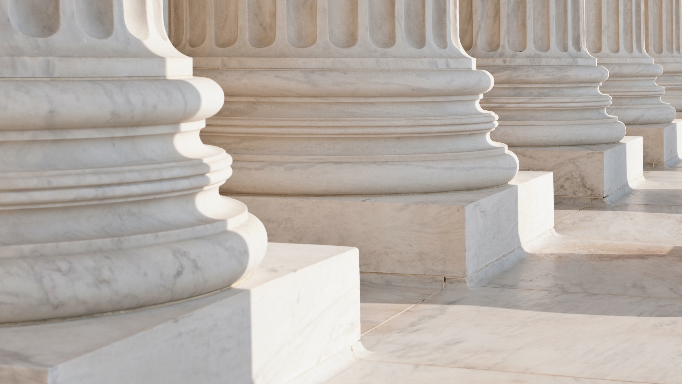 The architectural detail of several solid, elegant marble columns.